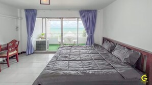 A bedroom with a large bed, a chair, and a view of the ocean through a sliding door. - GAO Phala Ocean View Pool Villa (Ban Chang)