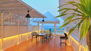 A terrace with a wooden table and chairs, a grill, and a view of the ocean. - GAO Phala Ocean View Pool Villa (Ban Chang)