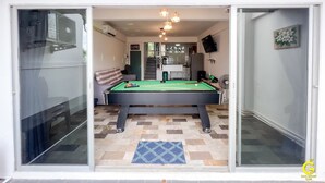 A pool table in a room with a sofa, a staircase, and a fan. - GAO Phala Ocean View Pool Villa (Ban Chang)