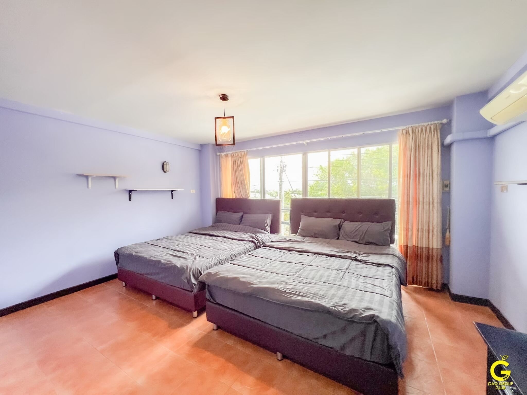 A bedroom with two beds, a window with curtains, a wall-mounted shelf, and a ceiling light.