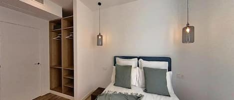 Quarto com cama, mesas de cabeceira, guarda-roupa e duas luzes pendentes.
