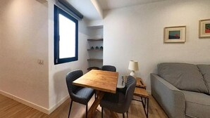 A compact living space with a dining table, two chairs, a sofa, and a small side table.
