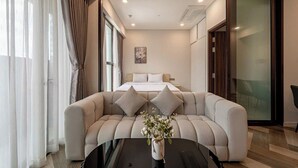 Een moderne hotelkamer met een bed, een bank, een bijzettafeltje en een bloemenvaas.