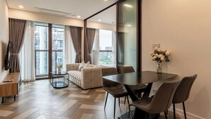 Een moderne woonkamer met een bank, eettafel, stoelen en een groot raam.