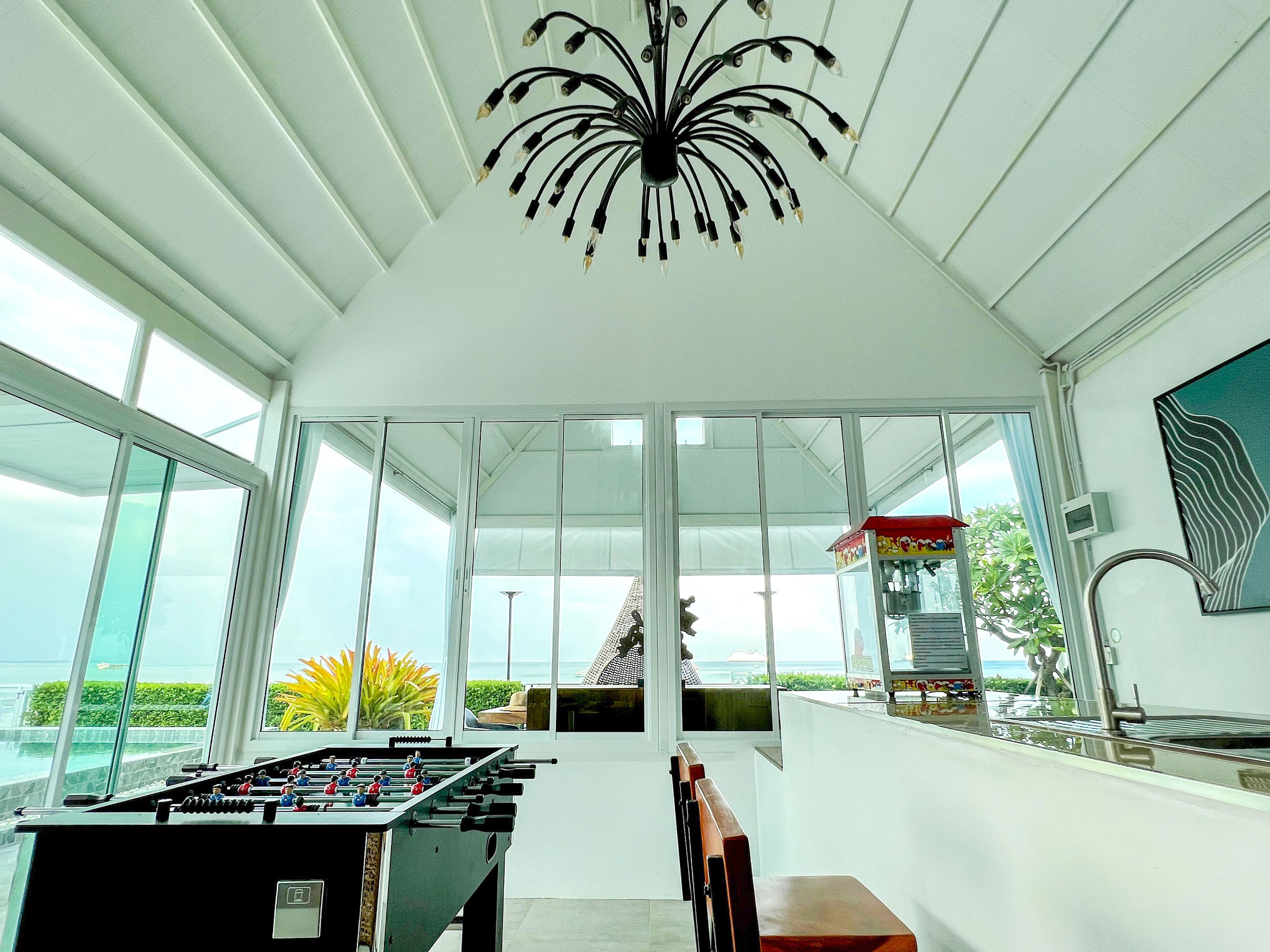 A spacious room with a foosball table, large windows, and a view of the sea.