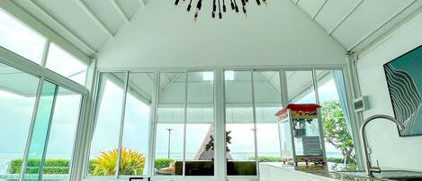 A spacious room with a foosball table, large windows, and a view of the sea.