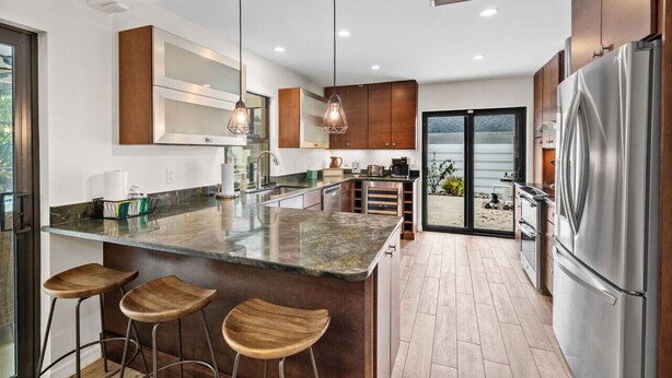 A modern kitchen with a large island, stainless steel appliances, and wooden bar stools.