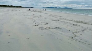 A wide beach with a cloudy sky.