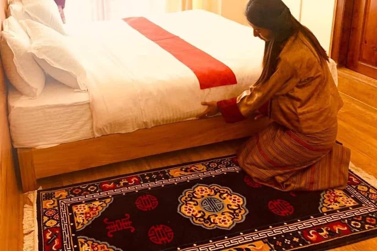 A bed with a red and white bedspread, a patterned rug, and a wooden floor.