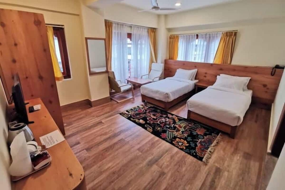 A hotel room with two beds, a desk, a chair, and a small table.