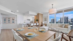 A modern apartment with a dining area, kitchen, and living space with a city view. - Modern Residence with Pool Access | Coconut Grove (Miami)