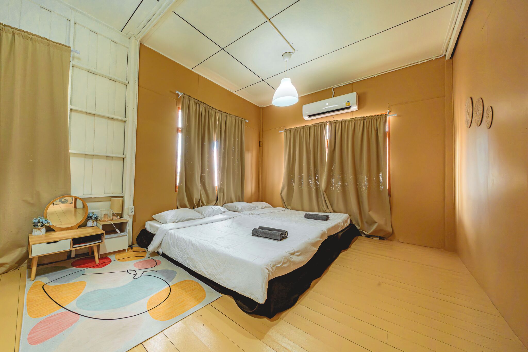 Un dormitorio con cama, mesita de noche, espejo y cortinas.
