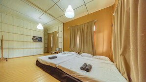A hotel room with a large bed, a wooden floor, a painting on the wall, and a ceiling light. - GAO Phala beachfront hostel & pool villa (Ban Chang)