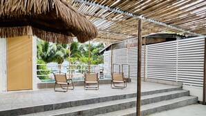A covered outdoor area with steps leading to a pool, featuring chairs and a thatched roof. - GAO Phala beachfront hostel & pool villa (Ban Chang)