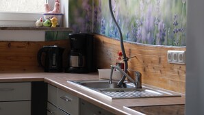 Eine Küche mit Holzausziehtisch, Spüle, Kaffeemaschine und Fenster mit Blick auf Blumen.