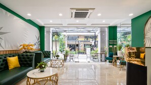 A modern lobby with a green sofa, a round table, and a seating area with chairs. - El Ocaso Boutique Hotel (Ho Chi Minh City)
