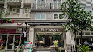 A multi-story building with a storefront named "El Ocaso" featuring a glass entrance and outdoor seating. - El Ocaso Boutique Hotel (Ho Chi Minh City)
