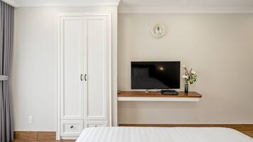 Een slaapkamer met een bed, een televisie op een plank, een kledingkast en een klok aan de muur.