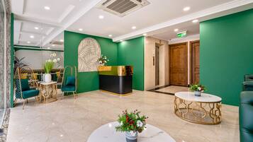 A lobby with a green wall, a reception desk, a wooden door, and a marble floor.