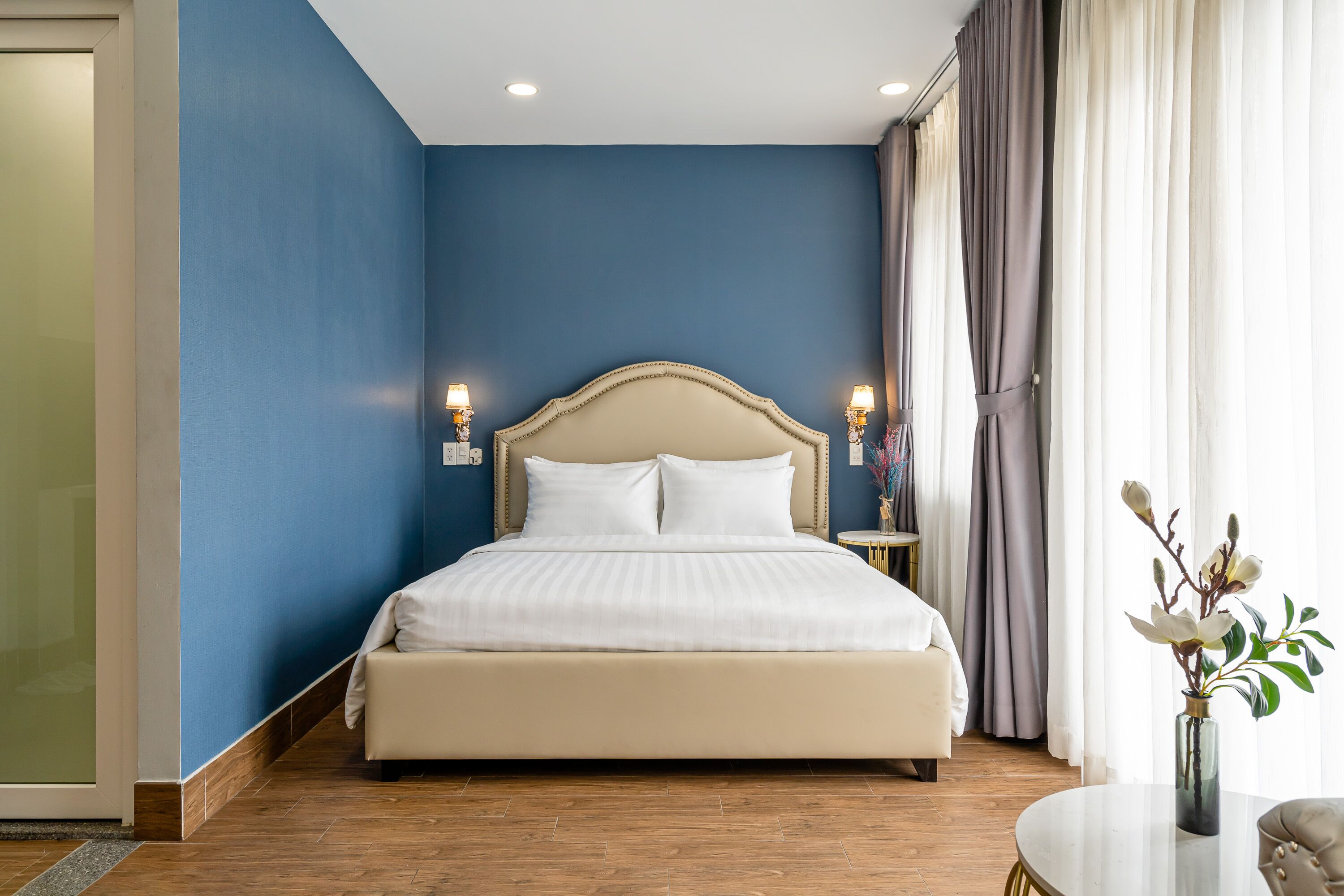 A bedroom with a large bed, blue walls, and a wooden floor.