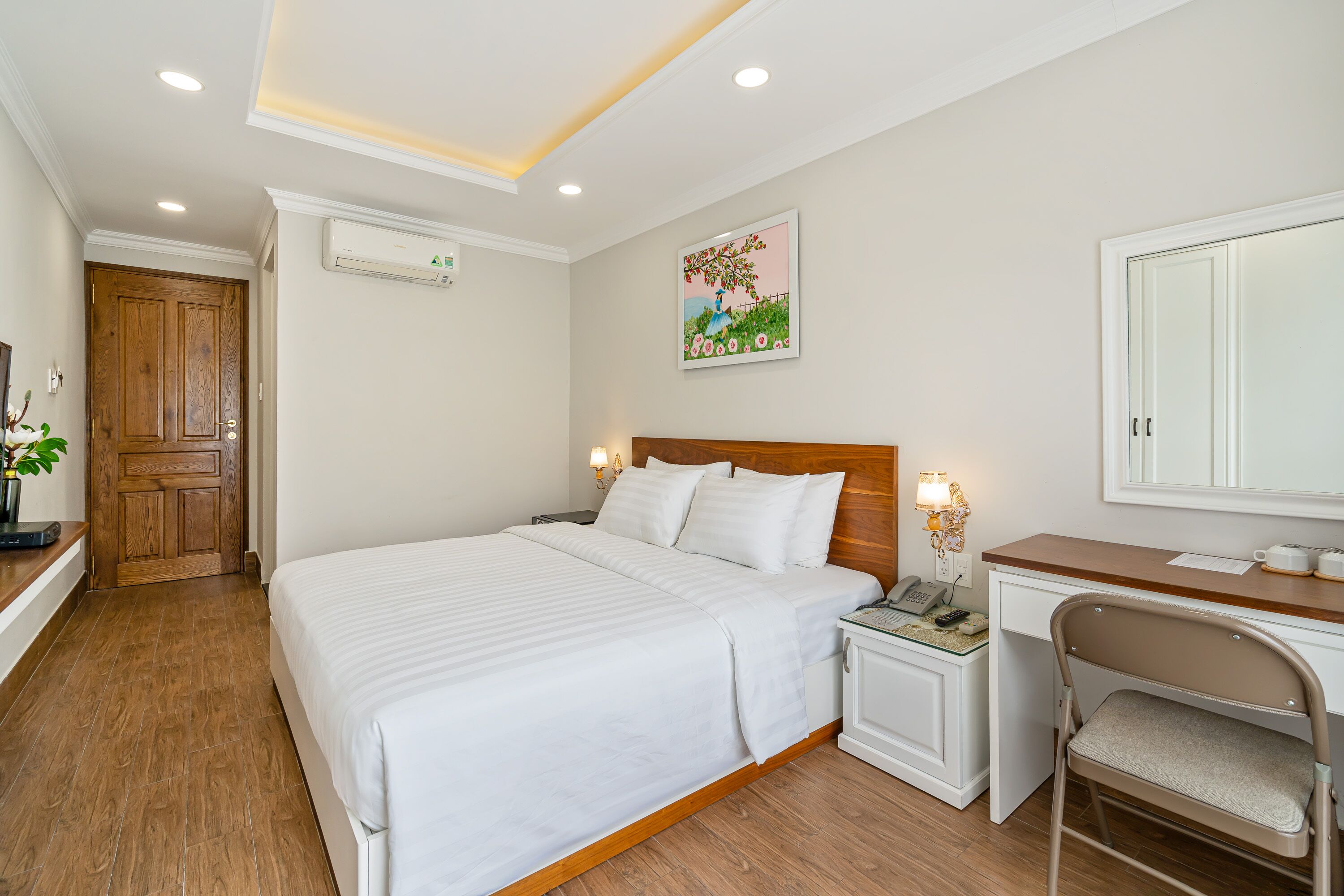 Un dormitorio ordenado con una cama grande, mesitas de noche, un escritorio y una silla.
