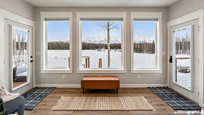 A room with large windows, a bench, and a rug.