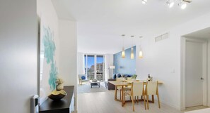 A modern living room with a dining area, large windows, and a view of the city.
