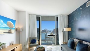 Una habitación de hotel moderna con balcón, un ventanal grande, sofá, escritorio y un mapa mural.