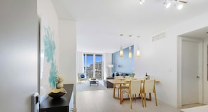 Una sala de estar moderna con comedor, ventanas amplias y vista a la ciudad.