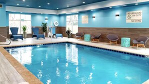 An indoor swimming pool with blue walls, seating areas, and a lifeguard sign. - Hampton Inn & Suites By Hilton Pittsboro (Pittsboro)
