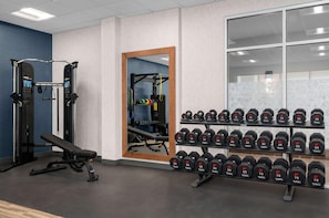 A gym with weightlifting equipment, a bench, and a rack of dumbbells. - Hampton Inn & Suites By Hilton Pittsboro (Pittsboro)