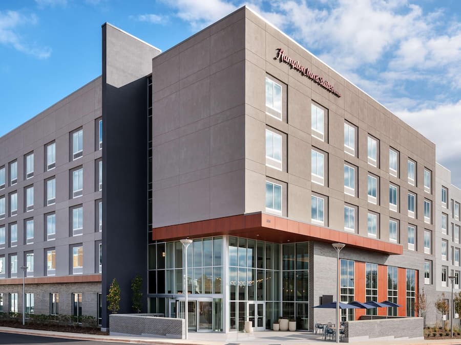 Un moderno edificio de hotel con una entrada destacada, ventanas amplias y un cielo despejado.