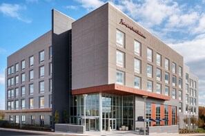 Un moderno edificio de hotel con una entrada destacada, ventanas amplias y un cielo despejado.