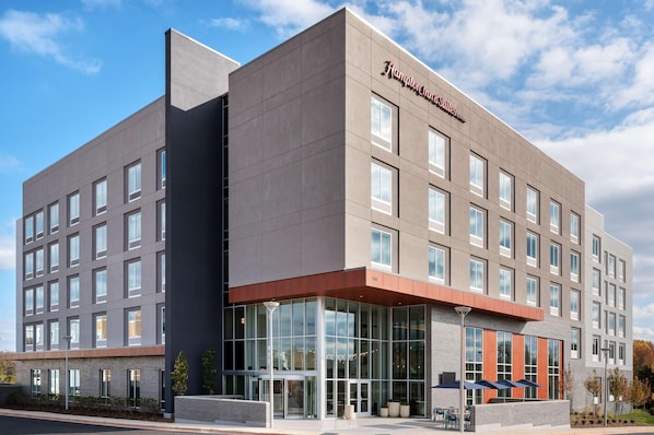 A modern hotel building with a prominent entrance, large windows, and a clear sky. - Hampton Inn & Suites By Hilton Pittsboro (Pittsboro)