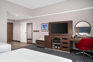 A hotel room with a bed, a desk with a computer, a TV, a microwave, and a red chair. - Hampton Inn & Suites By Hilton Pittsboro (Pittsboro)