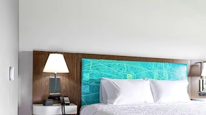 Habitación de hotel con cama, mesita de noche con lámpara y un diseño de circuito en la pared.