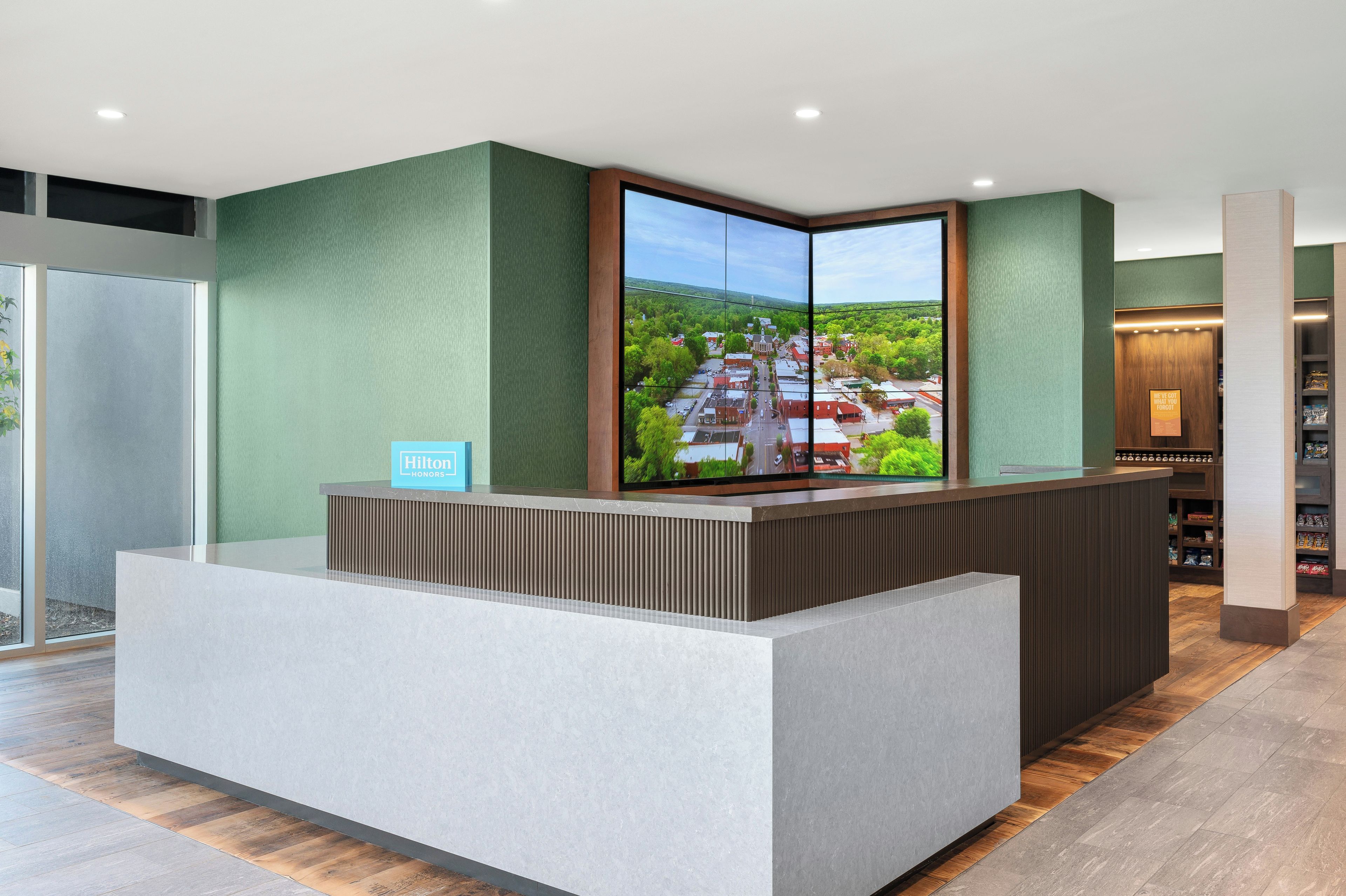A hotel reception desk with a large window displaying a view of a town.