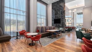 A spacious lobby with a seating area, a fireplace, and a large window. - Hampton Inn & Suites By Hilton Pittsboro (Pittsboro)