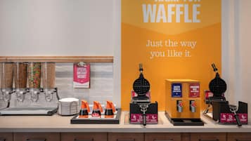 Una cocina con máquinas para hacer gofres, un cartel que dice "The Hampton Waffle" y un cartel preguntando sobre necesidades dietéticas.