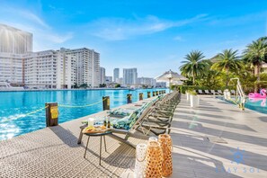 A poolside area with lounge chairs, a table with food, and a view of the city skyline.