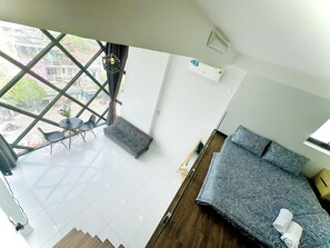 A modern room with a sofa, a dining table with chairs, and a large window with a view of the street. - Huyen Apartment (Ho Chi Minh City)