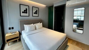 Ein modernes Schlafzimmer mit einem großen Bett, Nachttischen, einem Spiegel und Kunstwerken an der Wand.
