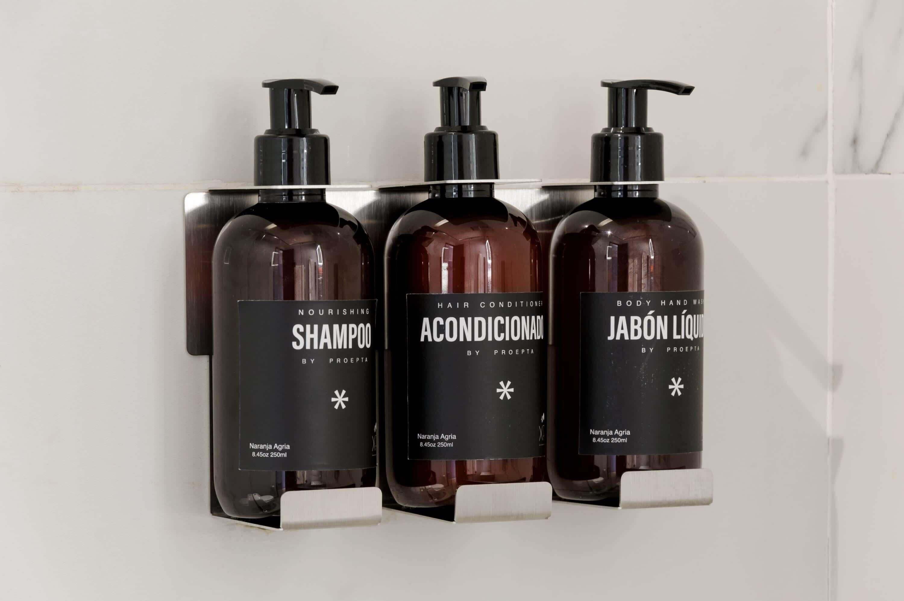 Tres botellas de productos para el cabello sobre un estante blanco.