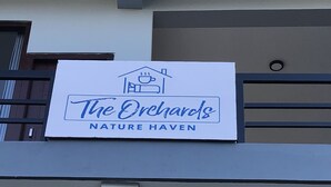 Señalización de 'The Orchards Nature Haven' con un icono de casa y taza.