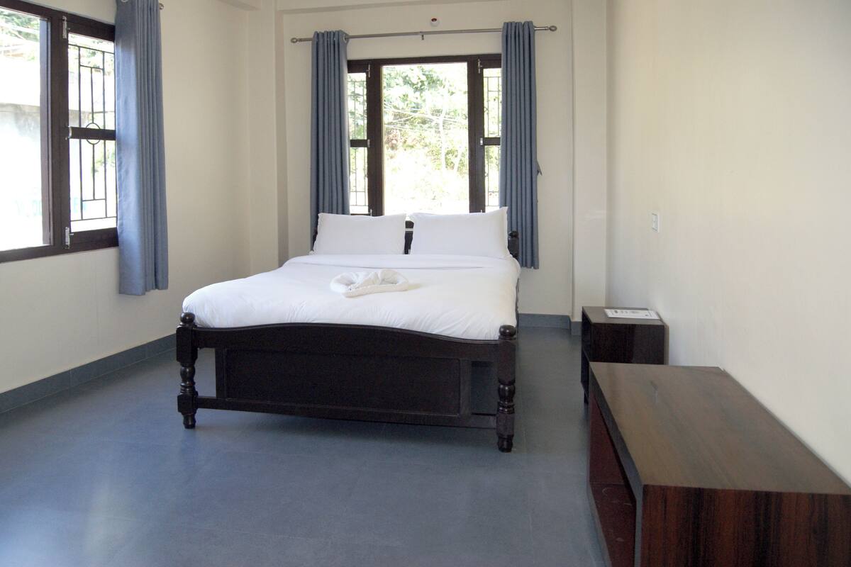 A bedroom with a wooden bed, a nightstand, and a window with curtains.