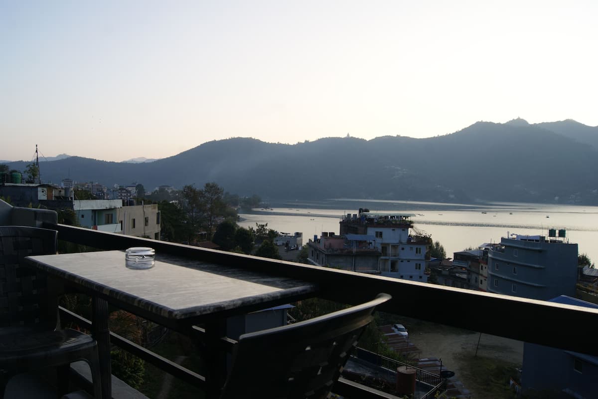 A balcony with a table and chairs overlooking a body of water and distant mountains.