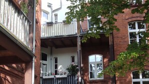 A courtyard with cobblestone ground, a bicycle, and a building with a balcony.