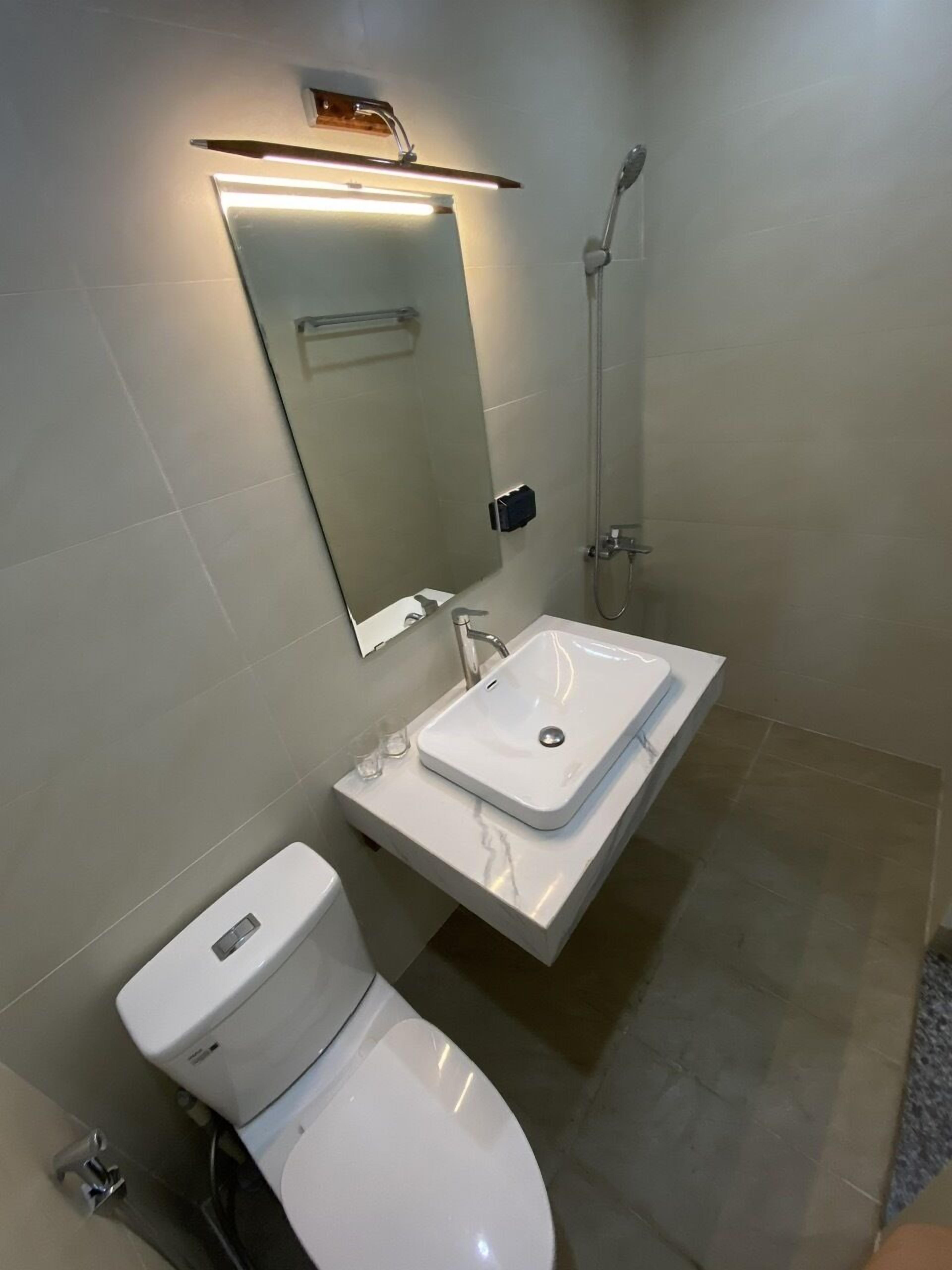 Ein modernes Badezimmer mit Waschbecken, Spiegel und Toilette in Weiß.