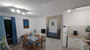 A compact living space with a dining area, kitchenette, and a large mirror.