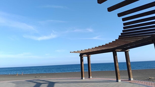 A wooden pergola structure with a view of the sea.